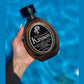 Hand holding Ed Hardy Coconut Kisses skin softening tanning lotion by pool