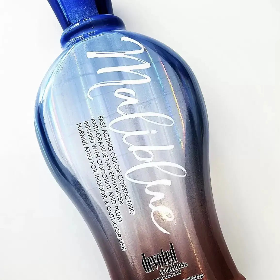 Close up of Devoted Creations Maliblue tanning lotion gradient packaging and shiny blue cap