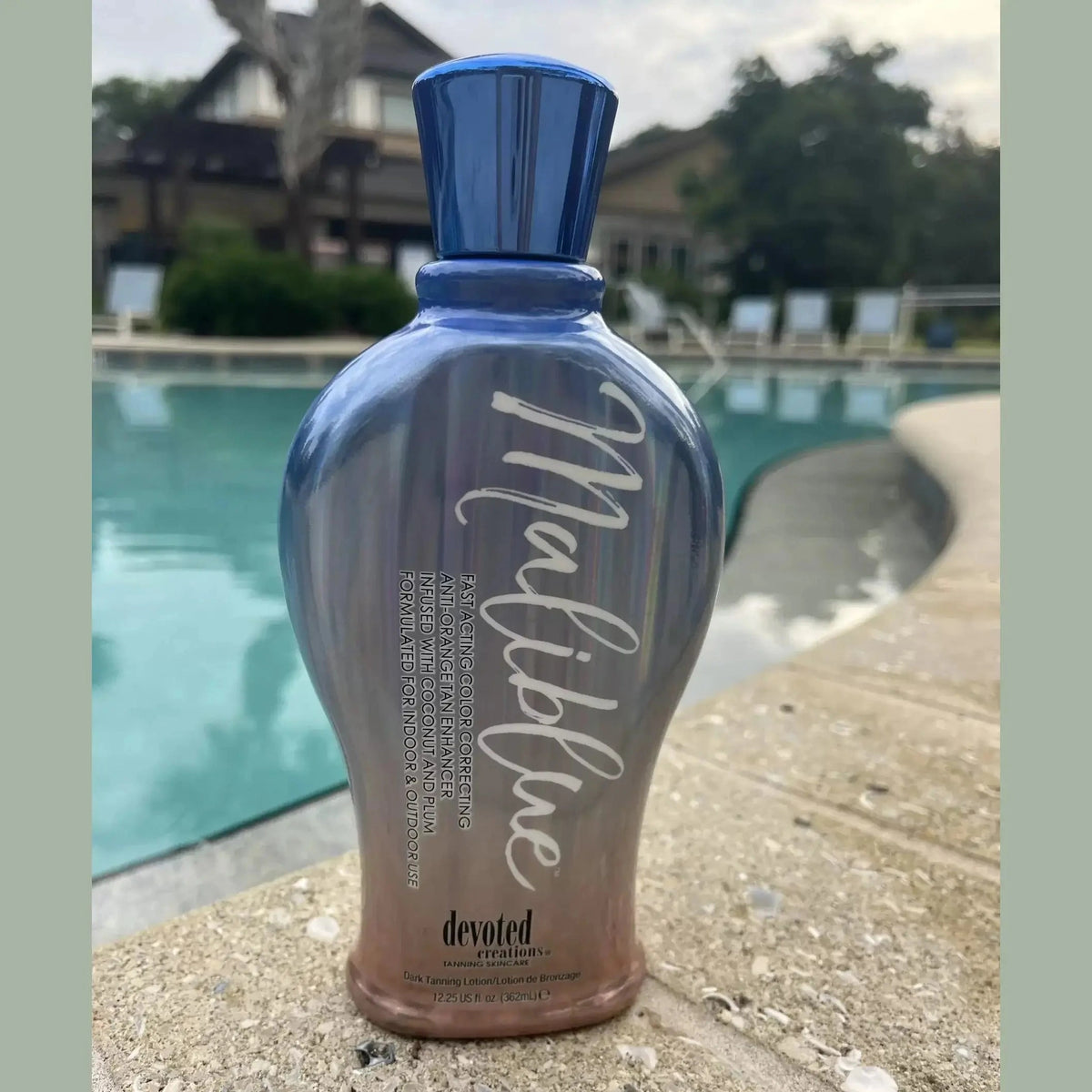 Devoted Creations Maliblue tan enhancer bottle on pool deck for outdoor use