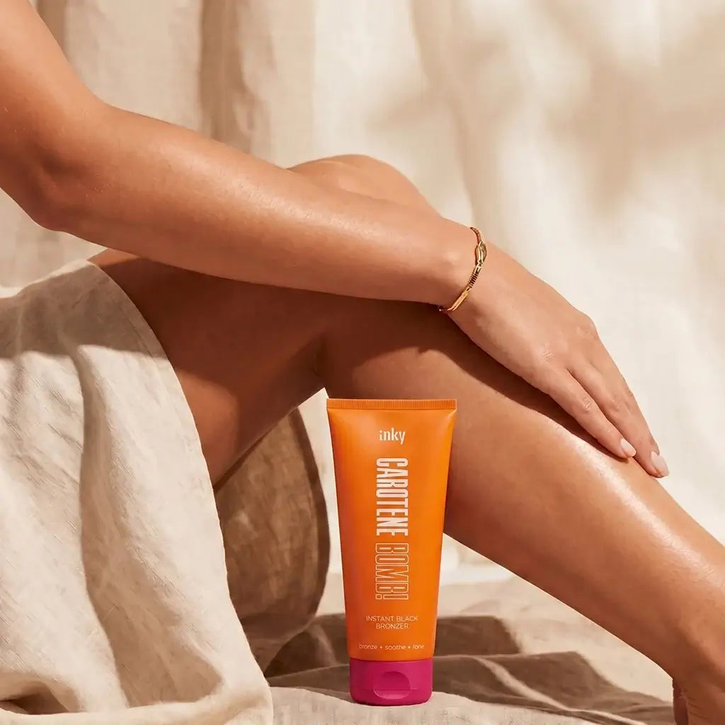 Inky Carotene Bomb instant black bronzing lotion tube on tanned legs