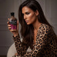 Model in leopard print holding Inky Leopard Vibe instant deep bronzing lotion bottle