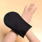 Black velvety self-tan mitt worn on hand for even mousse application